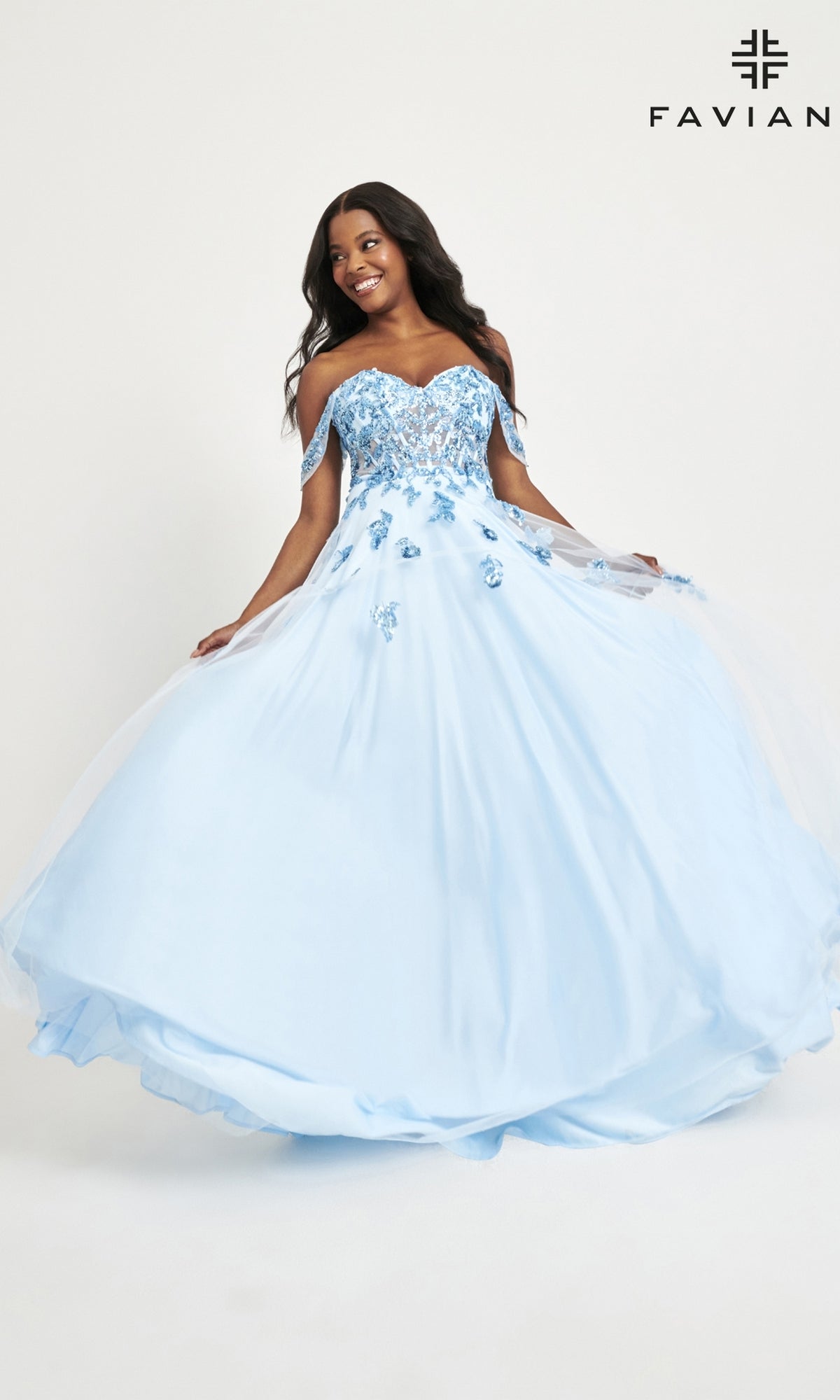 A woman twirls and smiles in the Faviana Off-Shoulder Long A-Line Prom Dress 11059, featuring a sheer corset bodice and floral appliqués. Its fitted top and flowing skirt create an elegant, romantic look against a plain background.